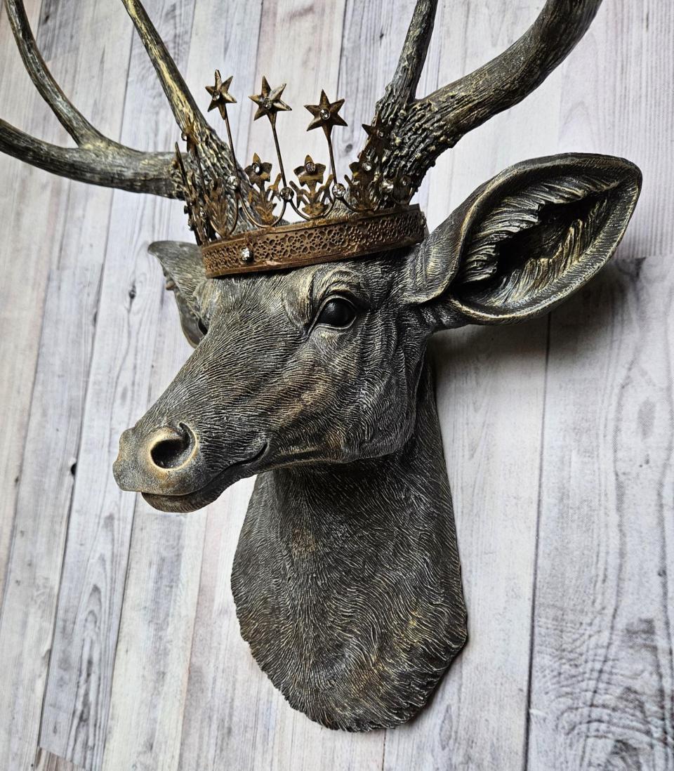 faux taxidermy deer head that's been painted chestnut brown with gold and antique white accents, the antlers are painted in the same color combination. A vintage bronze Santos metal crown with rhinestones accents the top of the deers head.