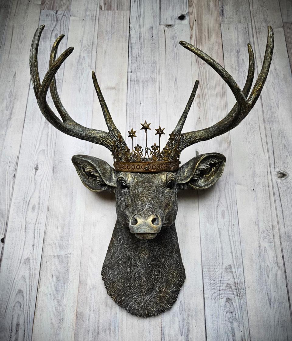 faux taxidermy deer head that's been painted chestnut brown with gold and antique white accents, the antlers are painted in the same color combination. A vintage bronze Santos metal crown with rhinestones accents the top of the deers head.