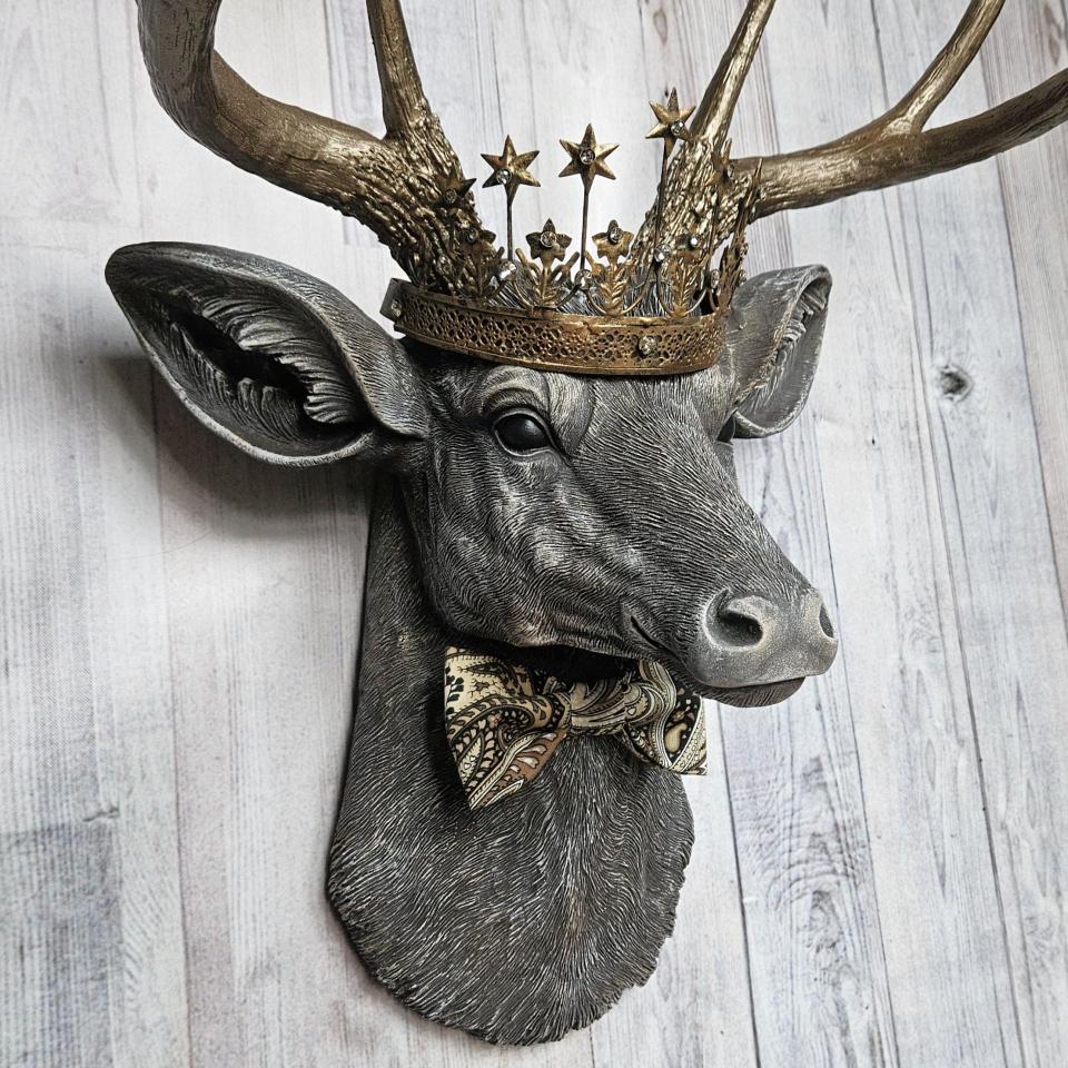 Faux taxidermy deer head wall mount with crown and bow tie.