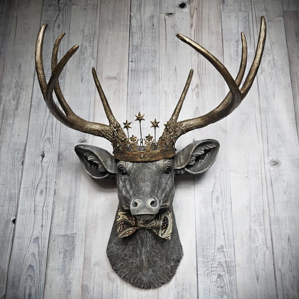 Faux taxidermy deer head wall mount with crown and bow tie.
