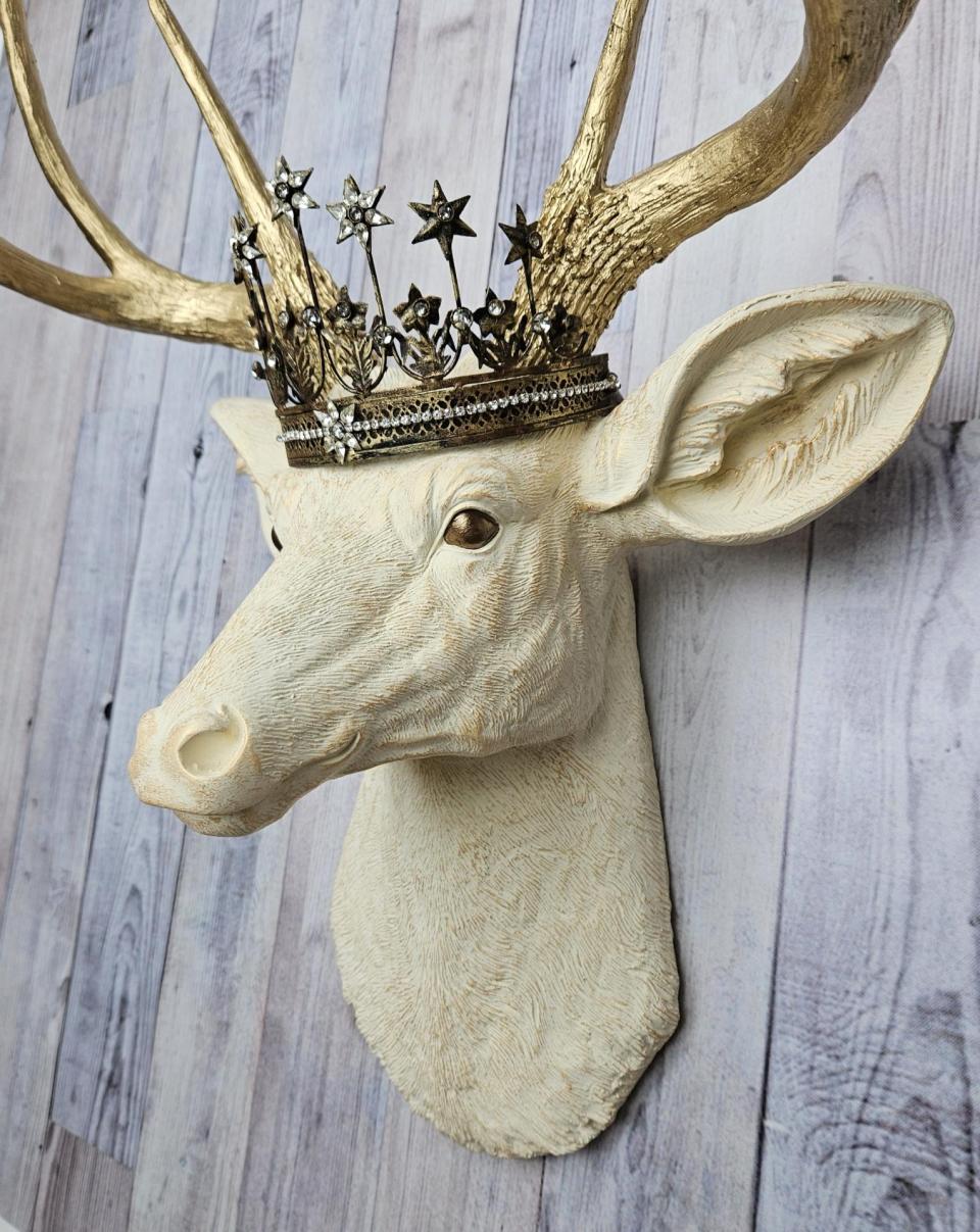Faux taxidermy deer head wall mount, painted antique white with gold accents and gold antlers. A vintage rhinestone encrusted Santos star crown rests atop the deers head.