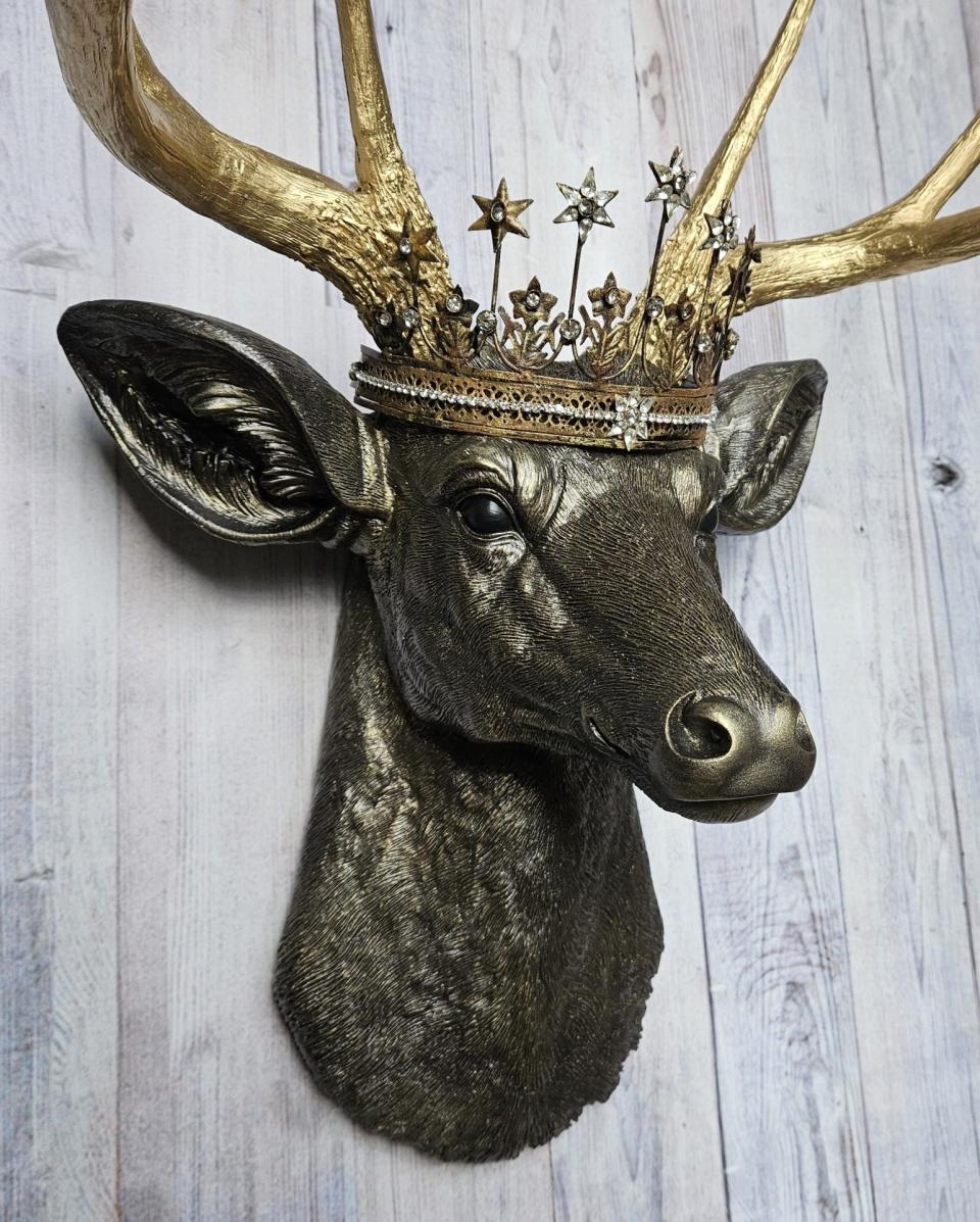 Faux taxidermy deer head wall mount, painted rubbed bronze with gold accents and gold antlers. A vintage rhinestone encrusted Santos star crown rests atop the deers head.