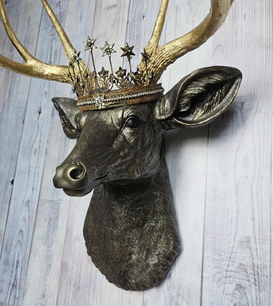 Faux taxidermy deer head wall mount, painted rubbed bronze with gold accents and gold antlers. A vintage rhinestone encrusted Santos star crown rests atop the deers head.