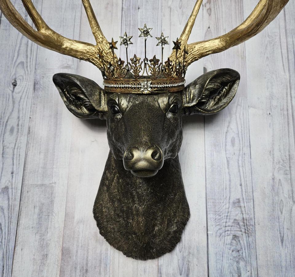 Faux taxidermy deer head wall mount, painted rubbed bronze with gold accents and gold antlers. A vintage rhinestone encrusted Santos star crown rests atop the deers head.