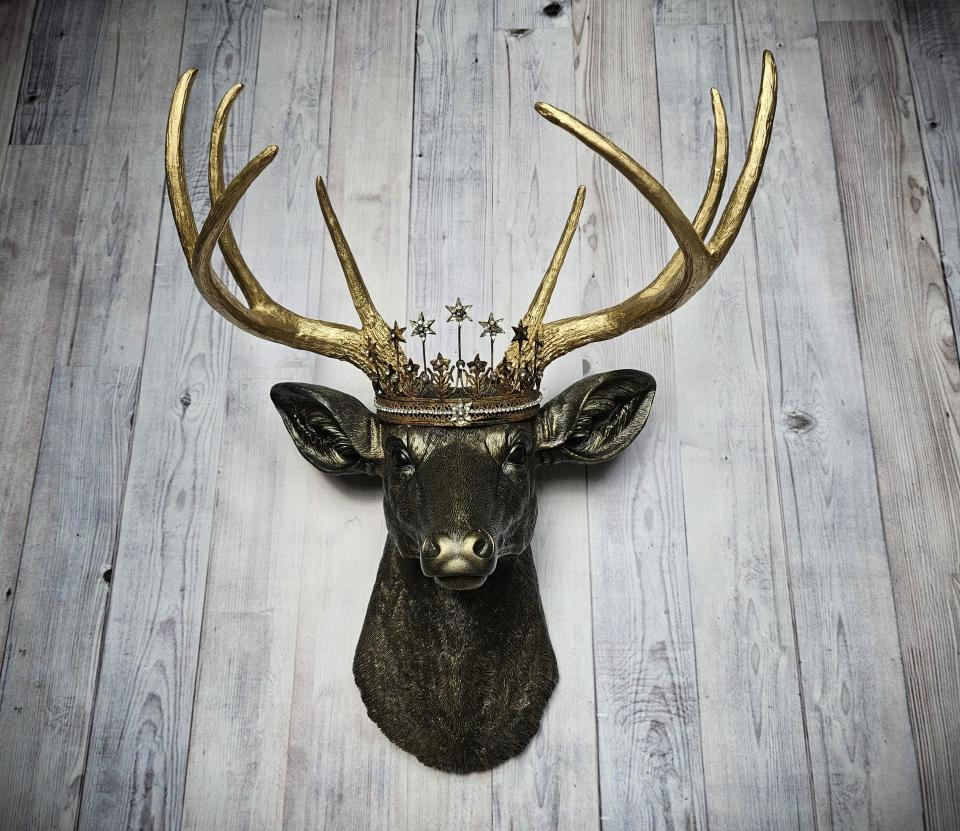 Faux taxidermy deer head wall mount, painted rubbed bronze with gold accents and gold antlers. A vintage rhinestone encrusted Santos star crown rests atop the deers head.