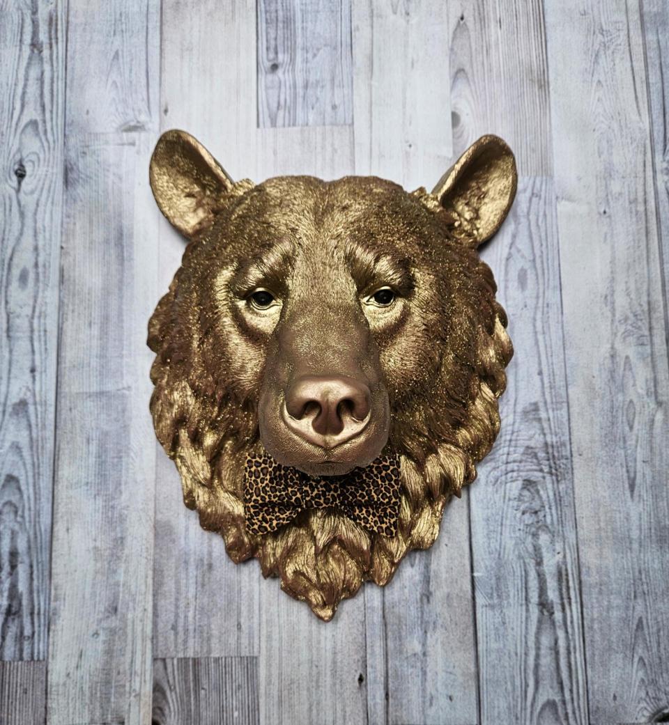 faux taxidermy bear head wall mount, painted gold with rose gold accents. a leopard bow tie accents the neck of the bear.