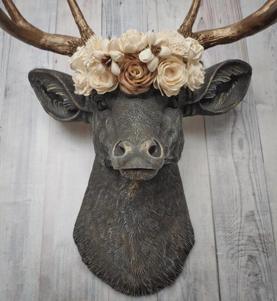 Faux taxidermy deer head, painted chestnut brown with antique white and gold accenting. The antlers are antique gold and a cream floral crown sits atop the deer head.
