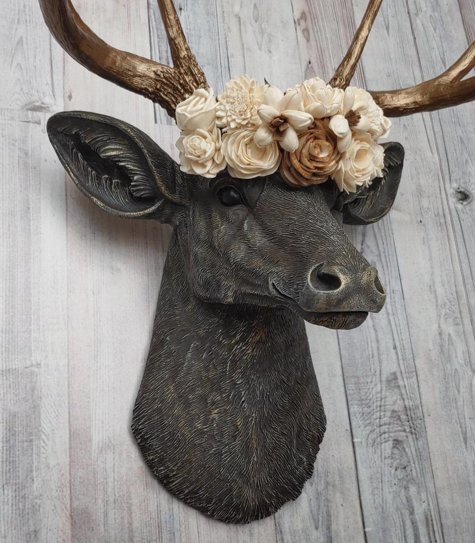 Faux taxidermy deer head, painted chestnut brown with antique white and gold accenting. The antlers are antique gold and a cream floral crown sits atop the deer head.