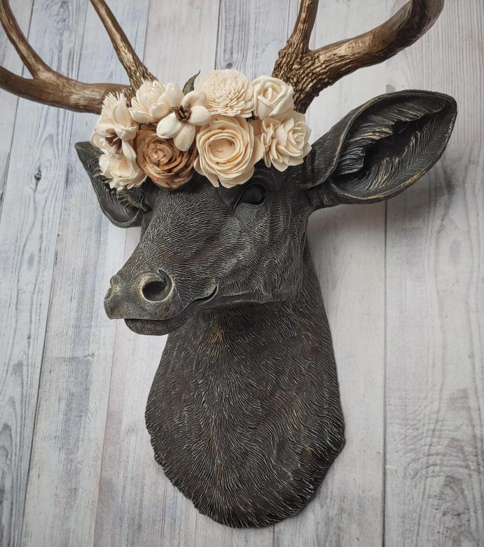 Faux taxidermy deer head, painted chestnut brown with antique white and gold accenting. The antlers are antique gold and a cream floral crown sits atop the deer head.