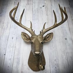 Faux taxidermy deer head wall mount with smoking pipe, painted antique gold with dark bronze accenting.