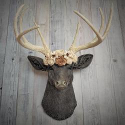 Faux taxidermy deer head, painted chestnut brown with antique white and gold accenting. Antlers are antique white with gold and chestnut brown accenting. A cream floral crown rests atop the deers head.