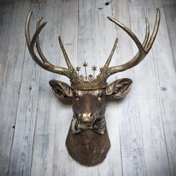 Faux taxidermy deer head wall mount with crown and bow tie.