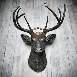 Faux taxidermy deer head wall mount. The head and antlers are black with dark copper accents. The deers head has additional accents in antique white, the eyes are black.A rustic vintage inspired star Santos crown sites atop the deers head.