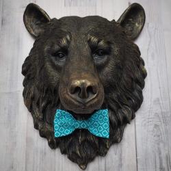 Faux taxidermy bear head wall mount, painted black with gold accenting. A turquoise and blue fabric bow tie accents the bears neck.
