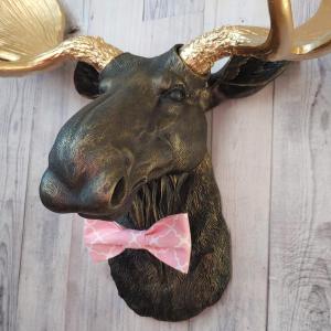 Faux taxidermy moose head, head is painted black with gold accents, antlers painted metallic gold, a pink quatrefoil bow tie accents the neck of the moose