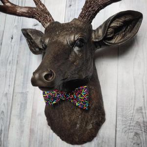 Faux taxidermy deer head, painted rubbed bronze with dark copper accenting on the head, antlers are dark copper. Removable bow tie, fabric is black with multi colored sprinkles.