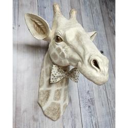 faux taxidermy giraffe head , painted antique white and gold with bronze accents. a white and gold polka dot bow tie accents the giraffes neck.