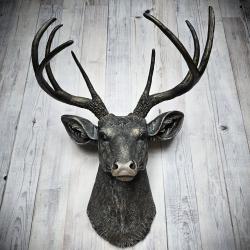 Faux taxidermy deer head wall mount. The head and antlers are black with dark copper accents. The deers head has additional accents in antique white, the eyes are black.