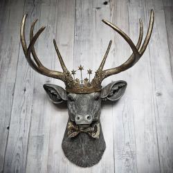 Faux taxidermy deer head wall mount with crown and bow tie.